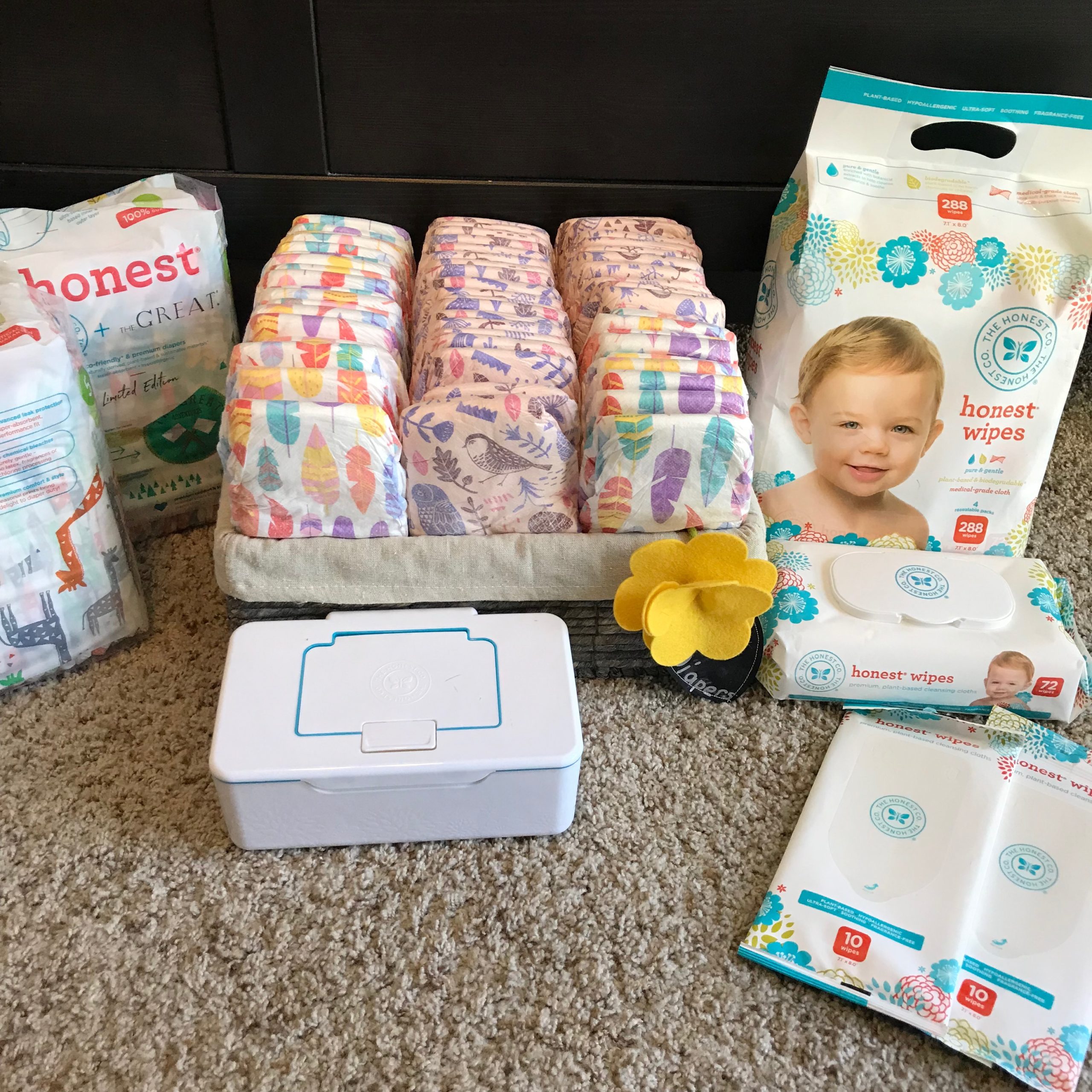 Diapers and wipes from The Honest Company arranged on a carpet