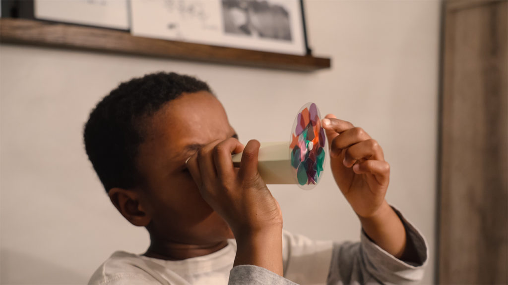 A kid looking through a Kiwi Crate Kaliedoscope