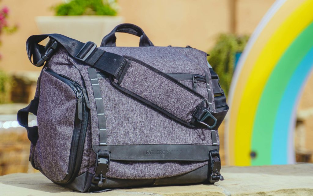 Fathercraft's diaper bag for dads outside with a rainbow behind it