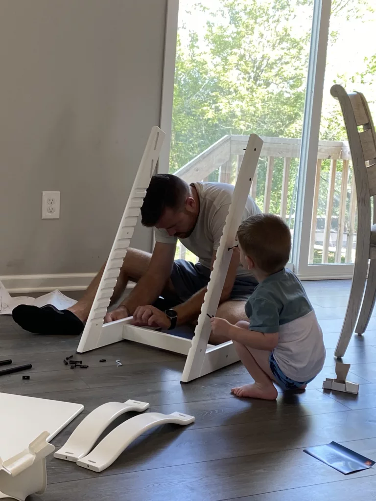 A dad and a toddler work on assembling the Stokke together